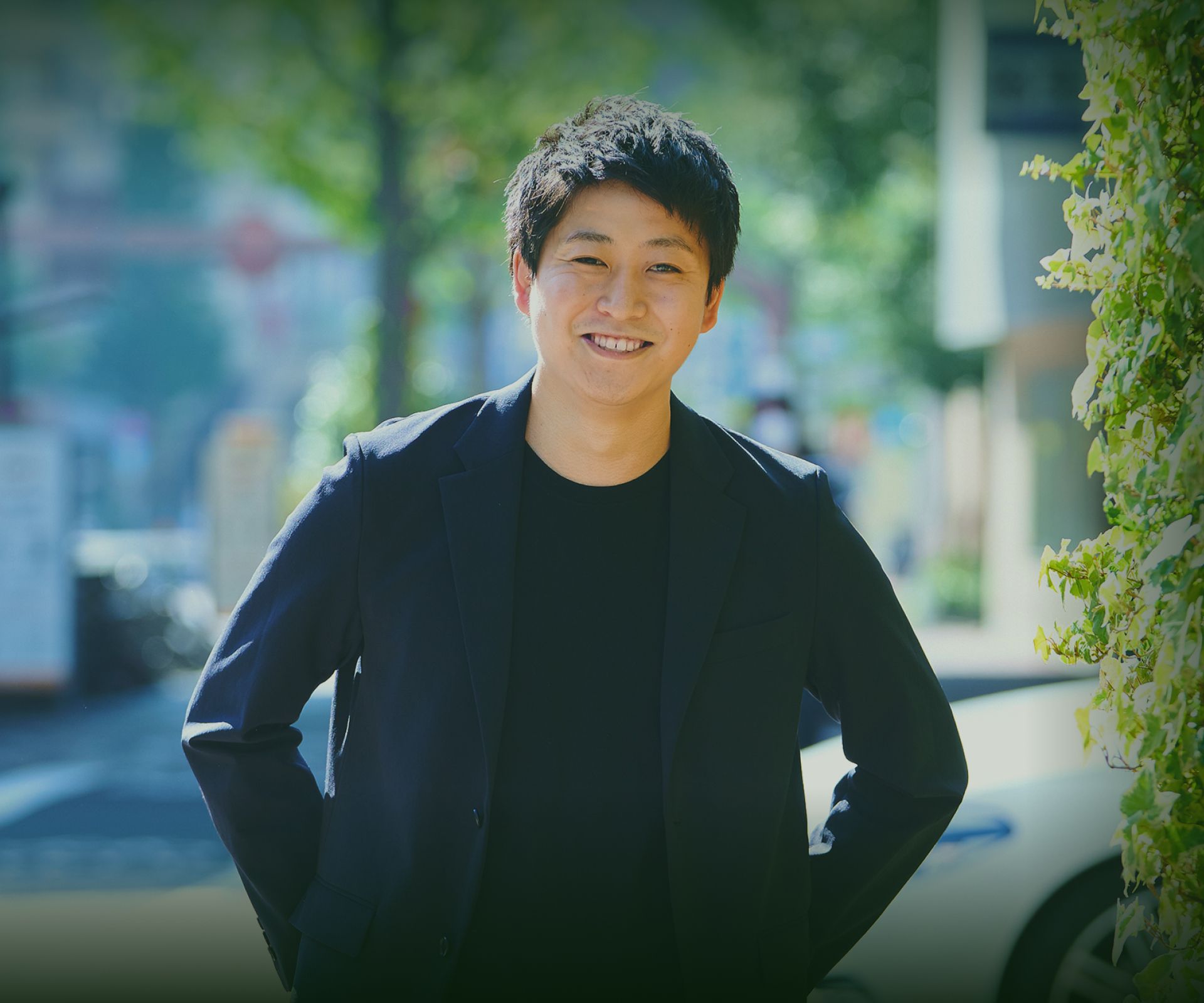 屋外で笑顔を見せるジャケット姿の男性