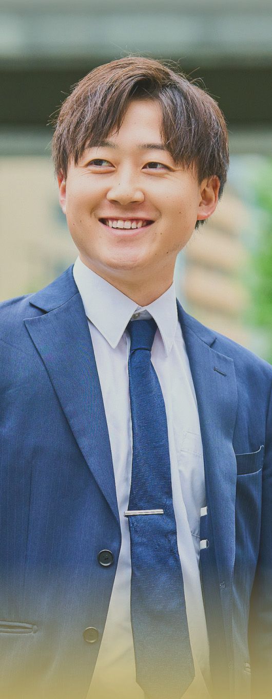 屋外で笑顔を見せるスーツ姿の男性
