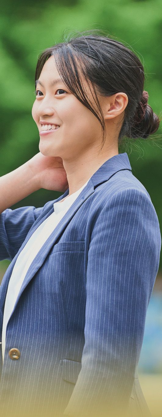 屋外で笑顔を見せるスーツ姿の女性